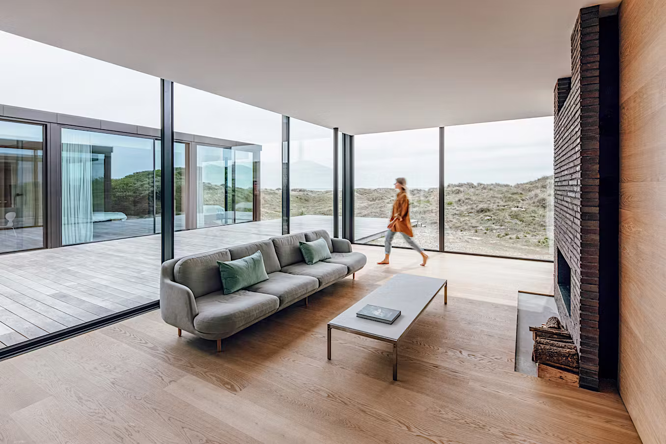 Open floor plan with floor-to-ceiling glass walls looking out to pool and garden